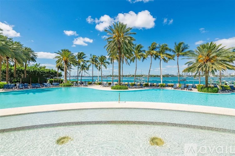 A pool surrounded by palm trees under a blue sky.
