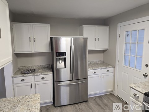 A kitchen with a stainless steel refrigerator and white cabinets.