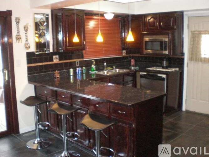 A kitchen with dark wood cabinets and a black countertop.