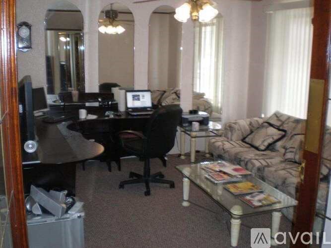 A living room with a couch, a desk with a computer, and a television.