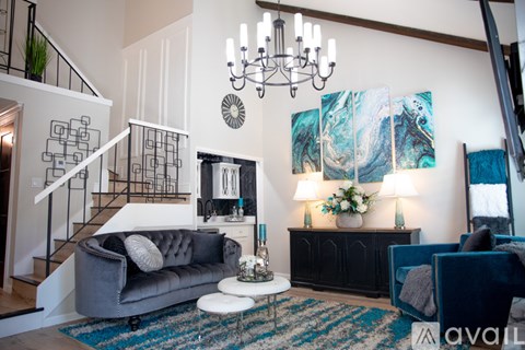 A living room with a grey couch and a chandelier.