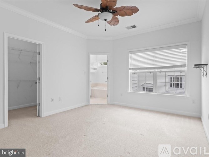 A spacious room with a ceiling fan and a window with blinds.
