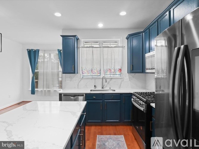 A kitchen with dark blue cabinets and a marble countertop.
