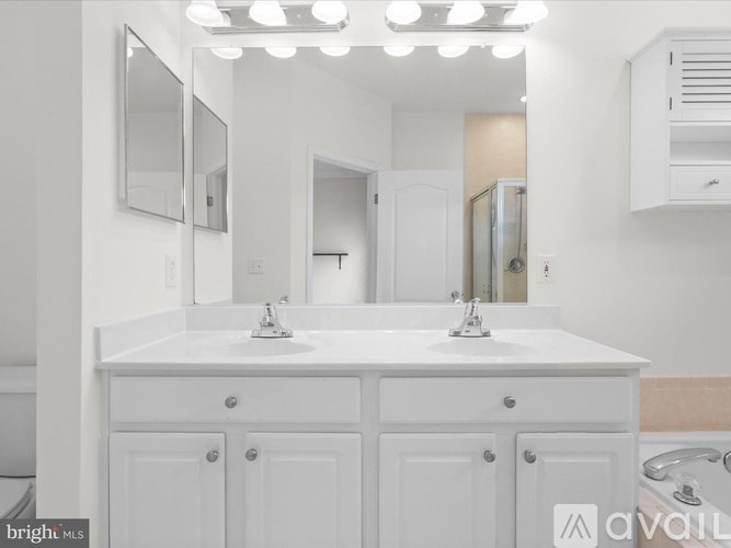 A white bathroom vanity with two sinks and a large mirror above it.