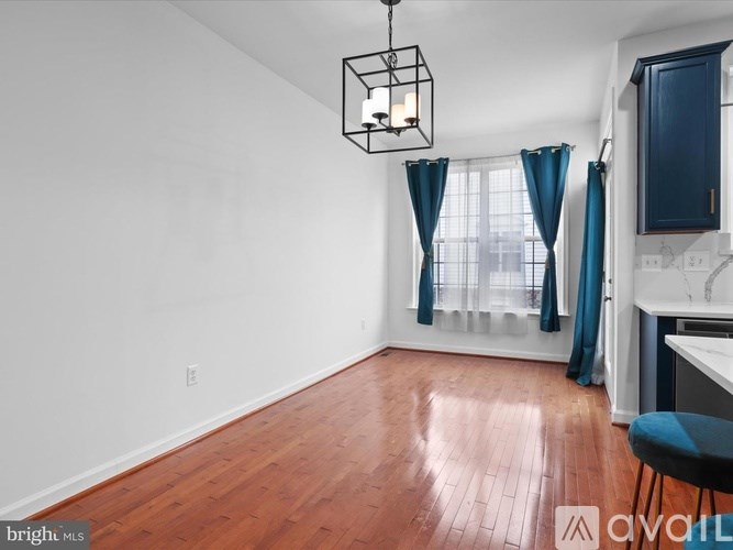 A room with wooden floors and a kitchen area with a sink and cabinets.
