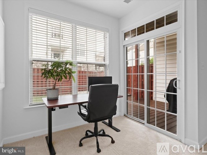 A room with a desk, chair, and a window with blinds.