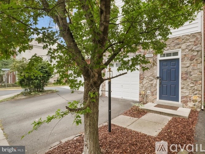 A tree in front of a house with a blue door.