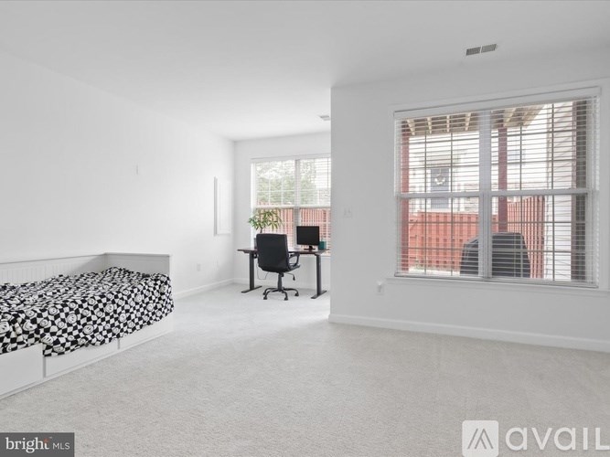 A bedroom with a bed, desk, and window.