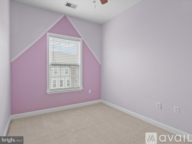 A room with a purple wall and a window with blinds.
