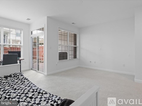A sparsely furnished living room with a black and white patterned rug.