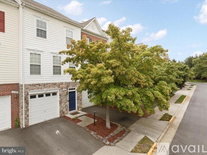 A tree in front of a white house with a garage door.