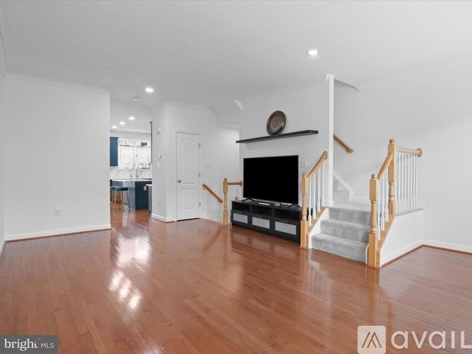 A spacious living room with a wooden floor and a staircase.