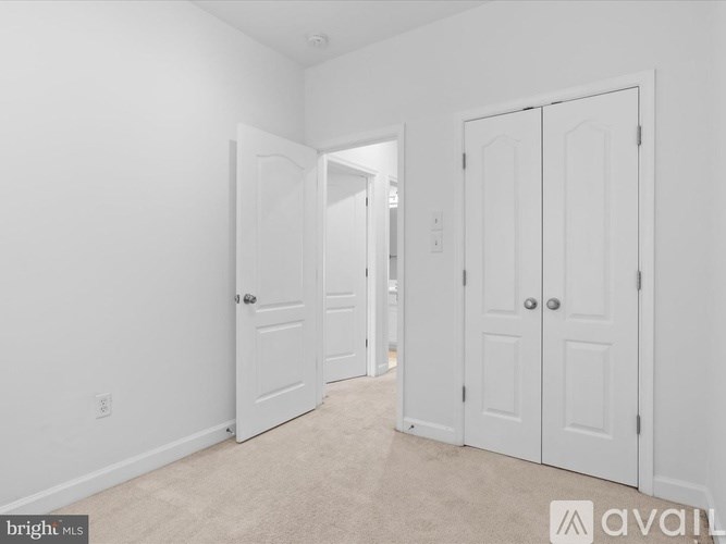 A white bedroom with two doors and a carpeted floor.