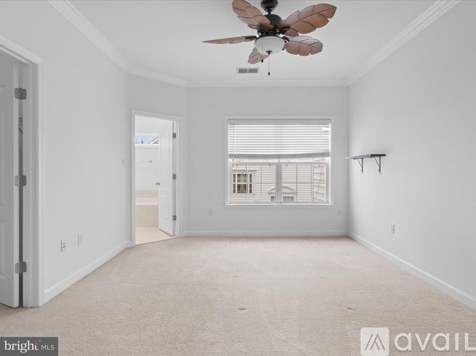 A spacious room with a ceiling fan and a window with blinds.