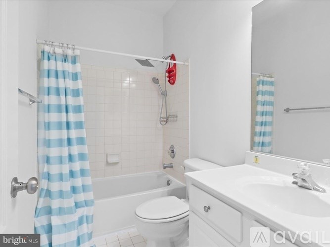 A white bathroom with a blue and white striped shower curtain.