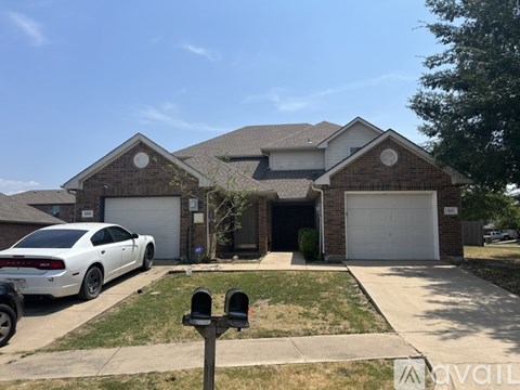 A white car is parked in front of a house with a garage.