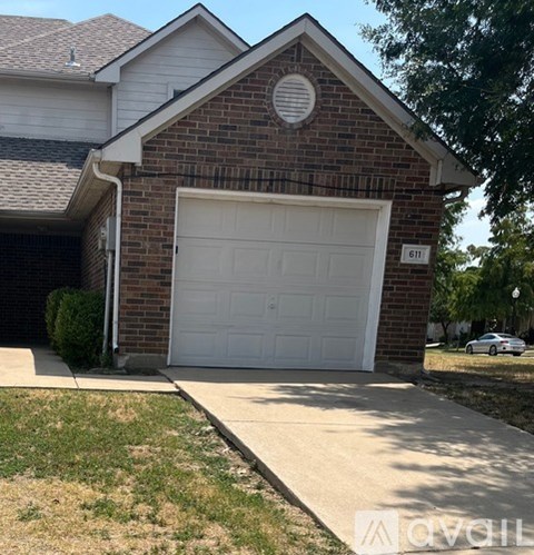 A brick house with a white garage door and number 611 on it.