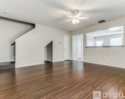 A spacious room with wooden flooring and a ceiling fan.