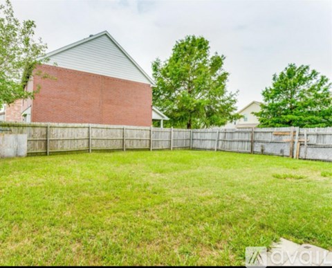 A grassy yard with a fence and a house in the background.