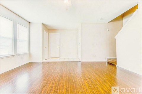 A room with wooden floors and white walls is available for rent.