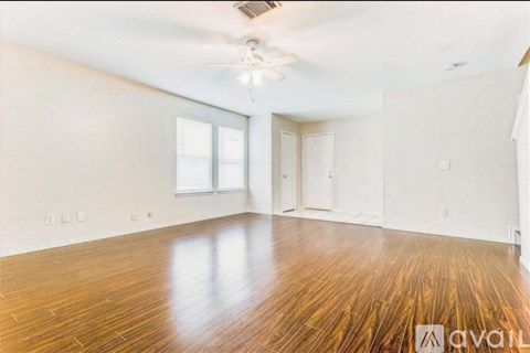 A spacious room with wooden floors and a ceiling fan.