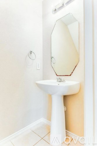 A white pedestal sink with a mirror above it.