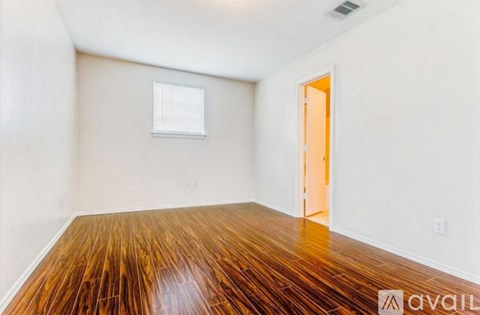 A room with wooden flooring and a door on the right side.