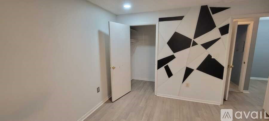 A room with a white door and a black and white geometric wall art.