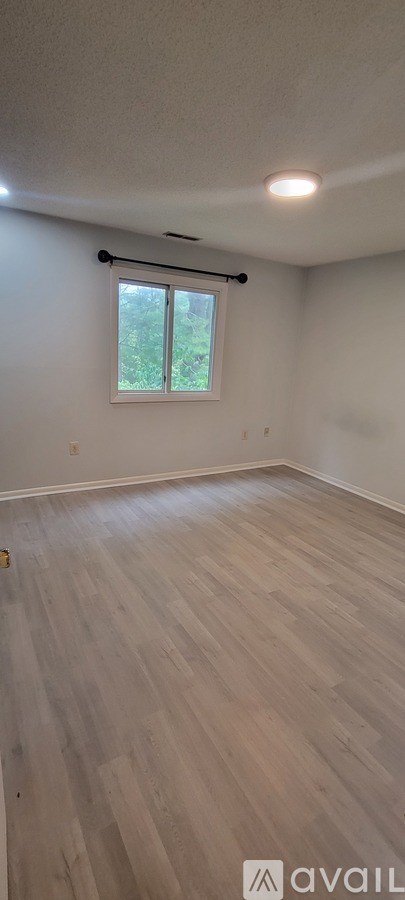 A room with wooden flooring and a window with blinds.