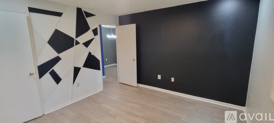 A hallway with a black wall and a white door.