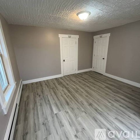A room with wooden flooring and two white doors.