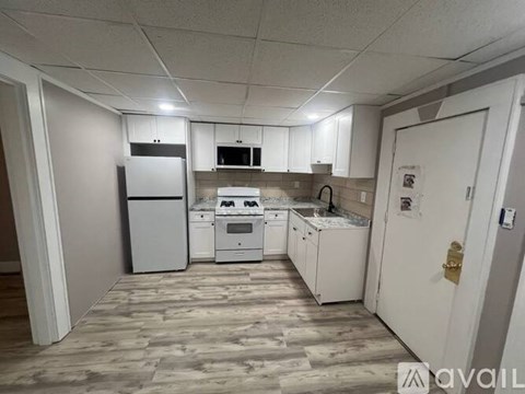 A kitchen with white appliances and cabinets is available for rent.