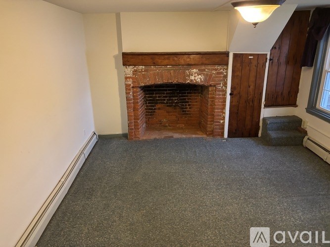 A room with a fireplace and a grey carpet.