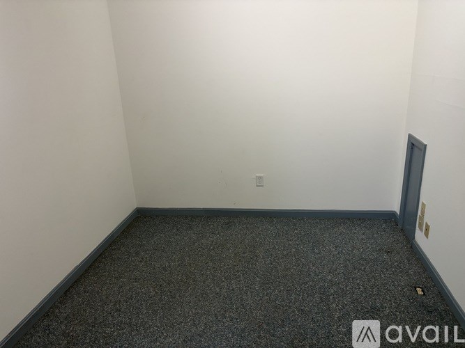 A room with a grey carpet and a door on the right side.