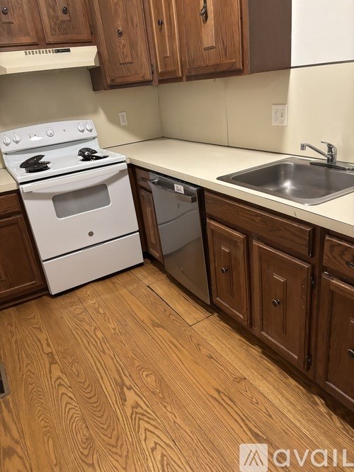 A kitchen with a white stove and wooden cabinets.