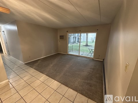 A room with a carpeted floor and a sliding glass door leading to a patio.