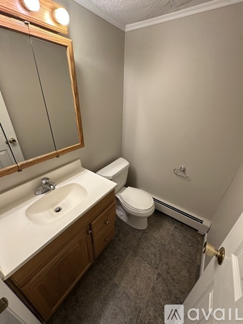 A bathroom with a sink, toilet, and mirror.