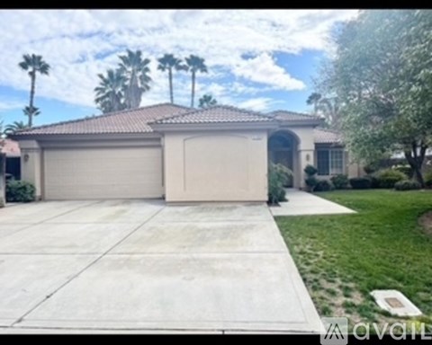 A house with a garage and palm trees in the background.