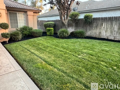 A well-maintained lawn in front of a house with a fence.