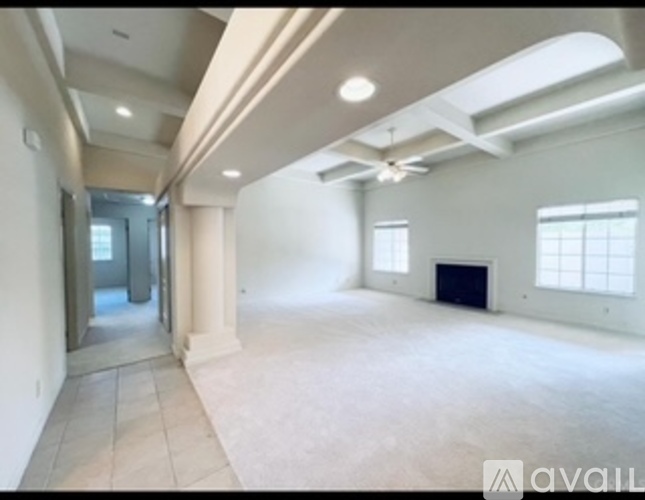 A spacious empty room with a skylight and a fireplace.