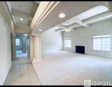 A spacious empty room with a skylight and a fireplace.