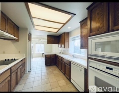 A kitchen with brown cabinets and white appliances.