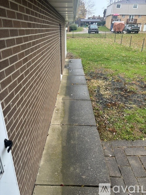 A brick wall with a white door and a concrete walkway.