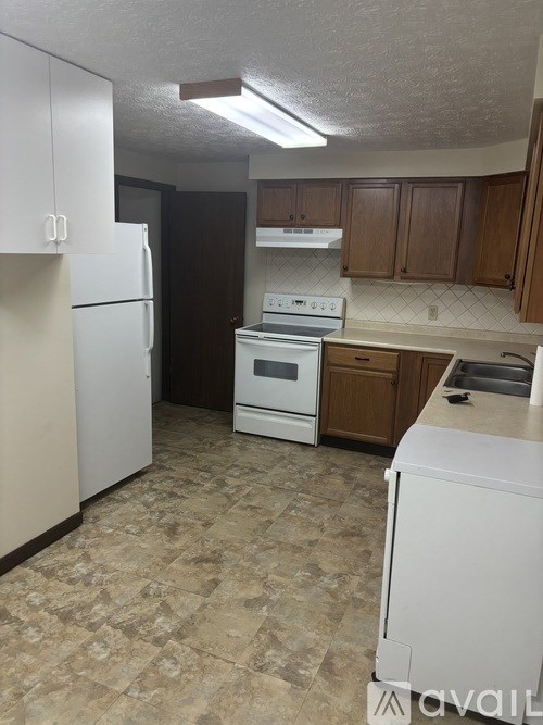 A kitchen with a white refrigerator, white oven, and brown cabinets.
