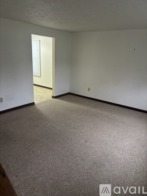 A room with a carpeted floor and a doorway leading to another room.