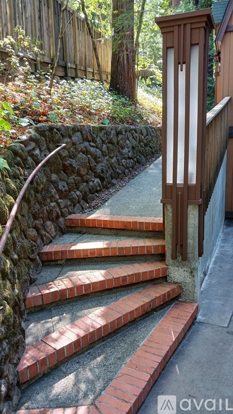 A set of stairs with a stone wall on one side and a wooden railing on the other.