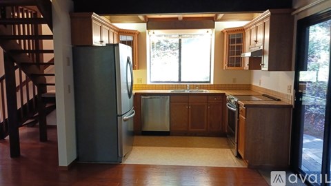 A kitchen with wooden cabinets and a stainless steel refrigerator.