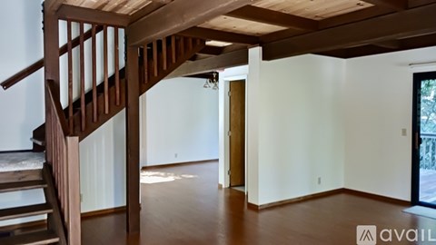 A wooden staircase leads to a brightly lit room with a door on the right.
