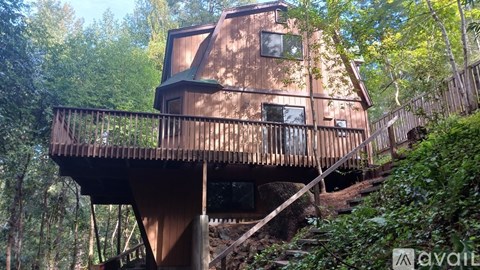 A treehouse with a balcony and stairs leading up to it.