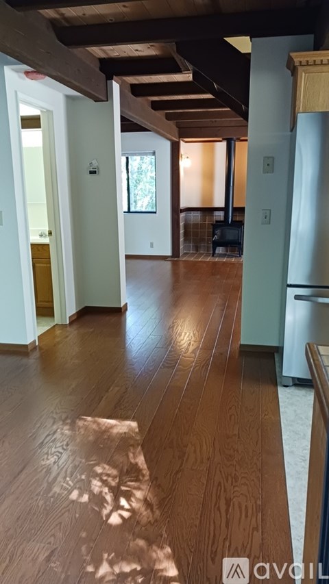 A long hallway with wood floors and a white door.